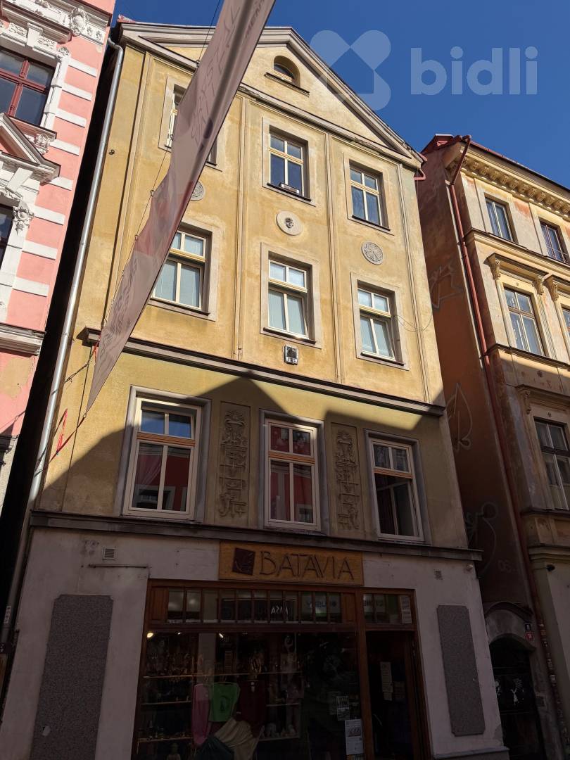 Čelní pohled na fasádu domu na Pražské s praporem nad ulicí
