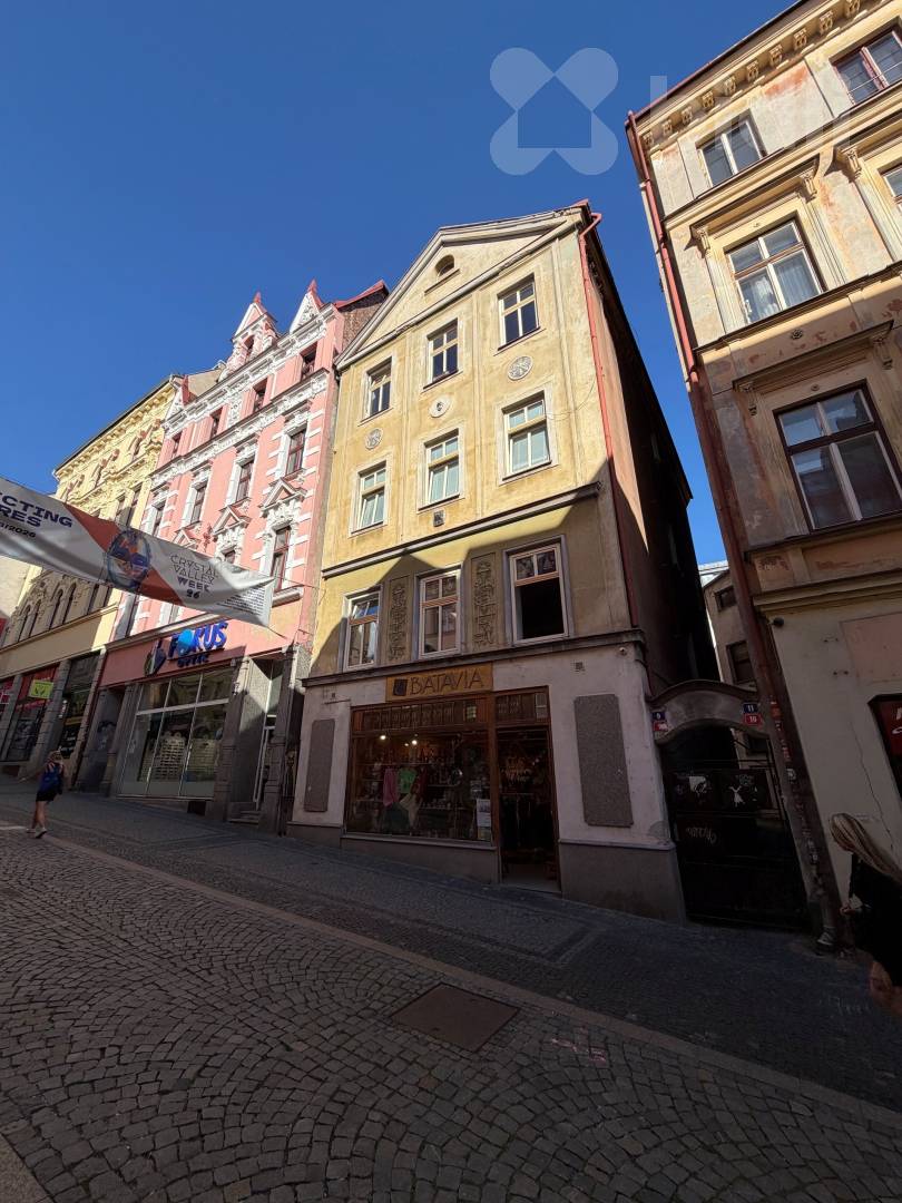 Celý okrový dům na Pražské s obchodem v přízemí, dlážděnou ulicí a modrým nebem